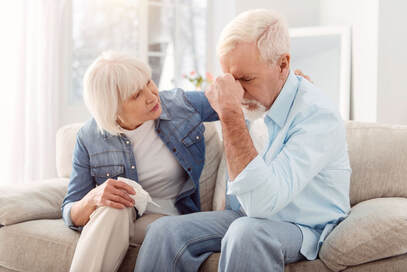 Confused elderly couple sitting on couch image